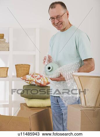 Stock Image - Man unpacking moving boxes. Fotosearch