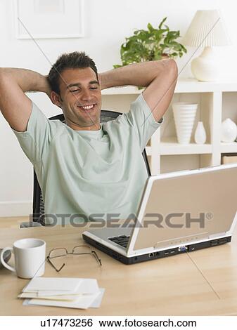 Stock Photograph - Man using laptop at table. Fotosearch