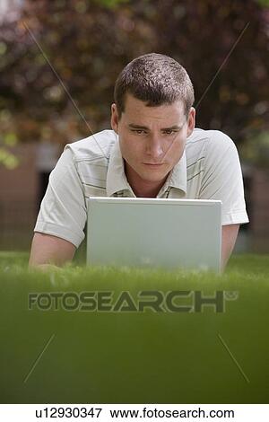 Man using laptop in grass View Large Photo Image Stock Photo - Man using laptop in grass. Fotosearch