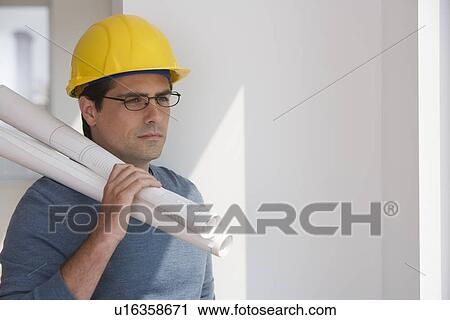 Man wearing hard hat and holding blueprints View Large Photo Image Stock Image - Man wearing hard hat and holding blueprints. Fotosearch