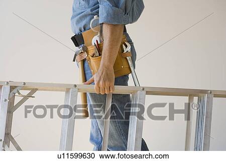 Man wearing tool belt and holding ladder View Large Photo Image Stock Image - Man wearing tool belt and holding ladder. Fotosearch