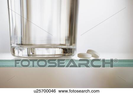 Stock Photograph - Medication and water glass on shelf. Fotosearch