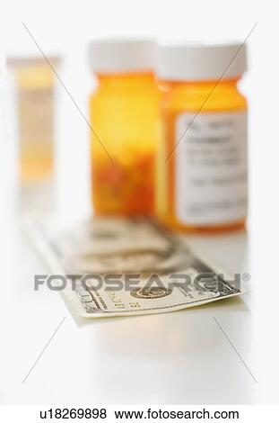 Stock Photo - Money in front of medication bottles. Fotosearch