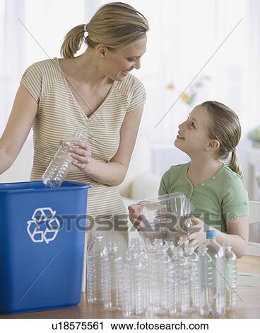 Stock Image - Mother and daughter filling recycle bin. Fotosearch