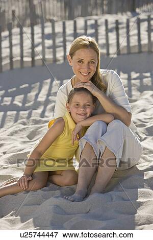 Stock Photo - Mother and daughter sitting on beach. Fotosearch