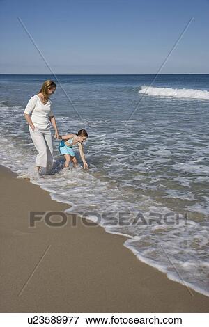 Stock Photo - Mother and daughter standing in ocean surf. Fotosearch