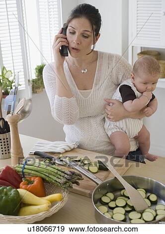 Mother holding baby, talking on telephone and cooking View Large Photo Image Stock Photo - Mother holding baby, talking on telephone and cooking. Fotosearch