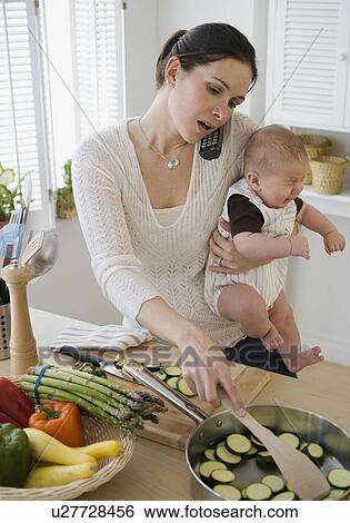 Mother holding baby, talking on telephone and cooking View Large Photo Image Stock Photograph - Mother holding baby, talking on telephone and cooking. Fotosearch