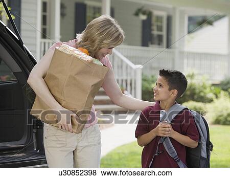 Stock Photo - Mother holding groceries and smiling at son. Fotosearch