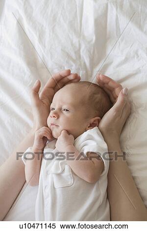 Mother holding hands around newborn baby's head View Large Photo Image Stock Photography - Mother holding hands around newborn baby's head. Fotosearch