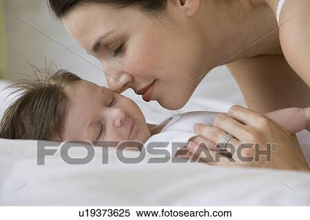 Stock Photography - Mother kissing sleeping baby. Fotosearch