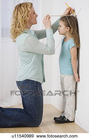 Mother marking daughter’s height on wall View Large Photo Image Stock Photo - Mother marking daughter’s height on wall. Fotosearch