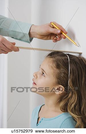 Stock Photo - Mother marking daughter’s height on wall. Fotosearch