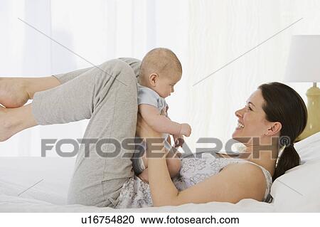 Mother playing with baby on bed View Large Photo Image Stock Image - Mother playing with baby on bed. Fotosearch