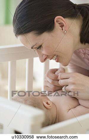 Mother smiling at baby in crib View Large Photo Image Stock Photo - Mother smiling at baby in crib. Fotosearch