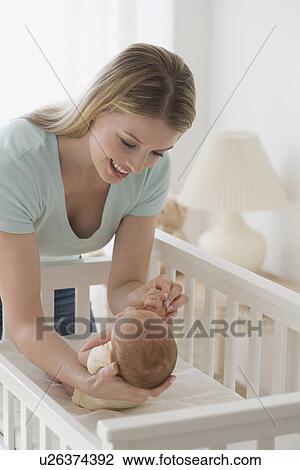 Stock Image - Mother smiling at newborn baby. Fotosearch