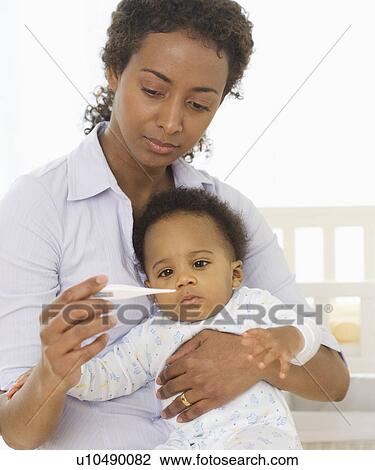 Stock Image - Mother taking baby’s temperature. Fotosearch