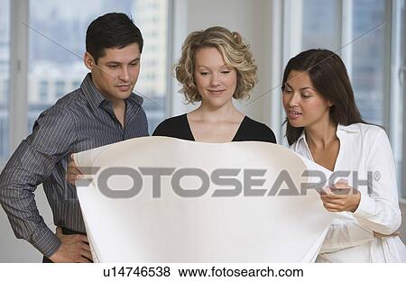 Stock Photo - Multi-ethnic businesspeople looking at blueprints. Fotosearch