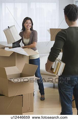 Multi-ethnic couple packing moving boxes View Large Photo Image Stock Photo - Multi-ethnic couple packing moving boxes. Fotosearch