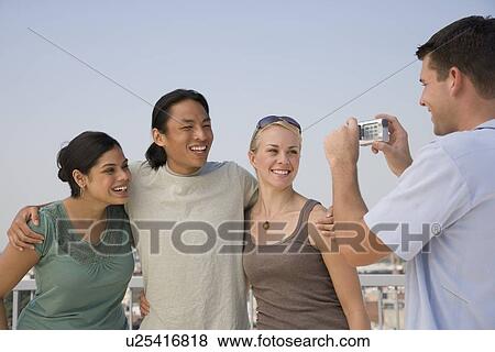 Stock Photo - Multi-ethnic friends having photograph taken. Fotosearch