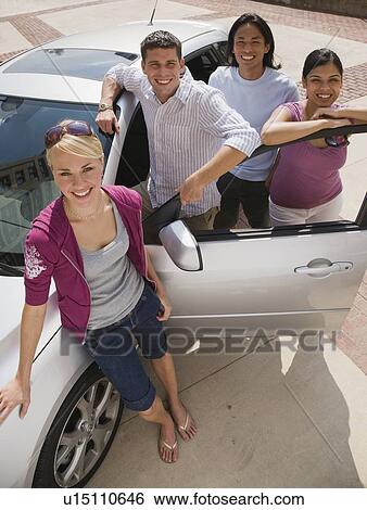 Stock Photograph - Multi-ethnic friends leaning on car. Fotosearch