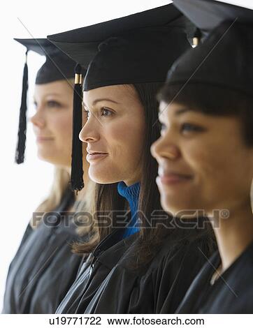 Stock Image - Multi-ethnic women wearing graduation cap and gown. Fotosearch