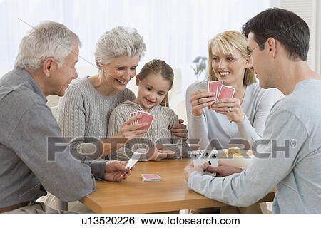 Stock Photograph - Multi-generational family playing cards. Fotosearch