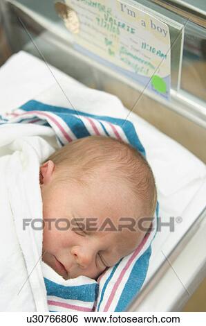 Stock Photograph - Newborn baby in hospital bed. Fotosearch