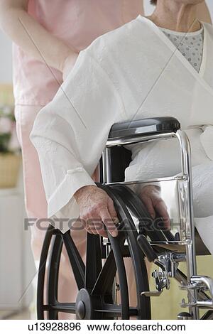 Stock Photograph - Nurse pushing senior woman in wheelchair. Fotosearch