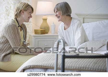 Picture - Nurse talking to senior woman in bed. Fotosearch