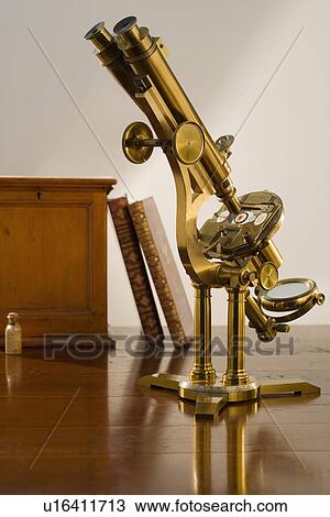 Stock Image - Old fashioned microscope on table. Fotosearch