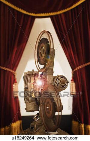 Picture - Old fashioned movie projector in between stage curtains. Fotosearch