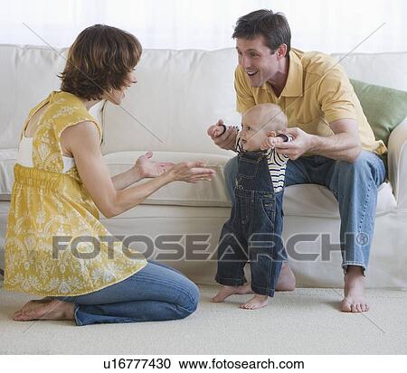 Stock Image - Parents helping baby walk. Fotosearch