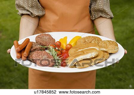 Stock Image - Person holding platter of food for barbeque. Fotosearch