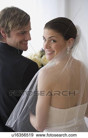 Stock Photo - Portrait of bride and groom looking over shoulders. Fotosearch