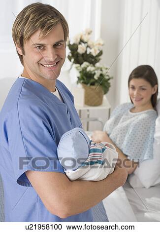 Stock Image - Portrait of father holding newborn baby in hospital. Fotosearch