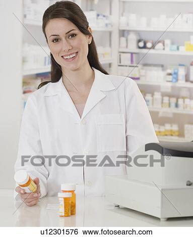 Portrait of female pharmacist holding medication View Large Photo Image Stock Photograph - Portrait of female pharmacist holding medication. Fotosearch