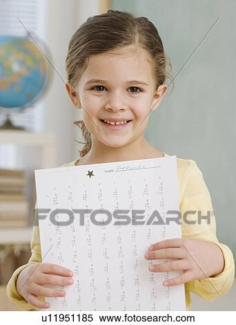 Stock Photography - Portrait of girl holding paper in school. Fotosearch