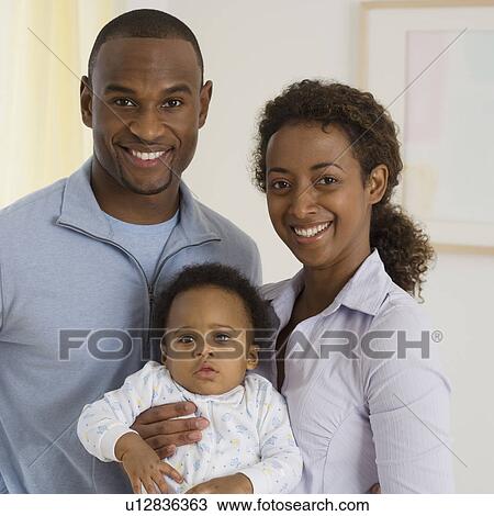 Stock Image - Portrait of parents holding baby. Fotosearch
