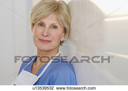 Stock Image - Portrait of senior female doctor against wall. Fotosearch