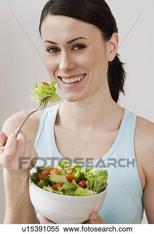 Stock Photography - Portrait of woman eating salad. Fotosearch