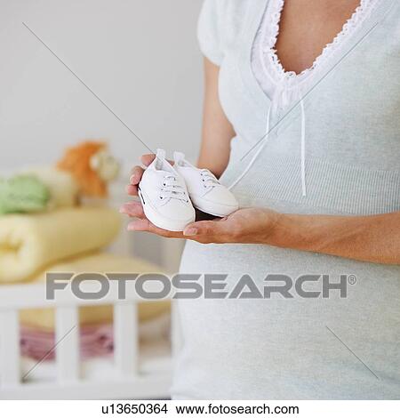 Pregnant woman holding baby shoes View Large Photo Image Picture - Pregnant woman holding baby shoes. Fotosearch