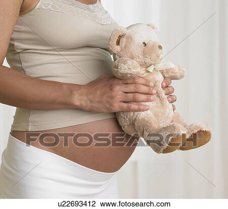 Pregnant woman holding teddy bear against stomach View Large Photo Image Stock Image - Pregnant woman holding teddy bear against stomach. Fotosearch