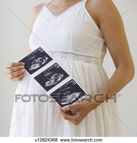 Pregnant woman holding ultrasound printout View Large Photo Image Stock Photo - Pregnant woman holding ultrasound printout. Fotosearch