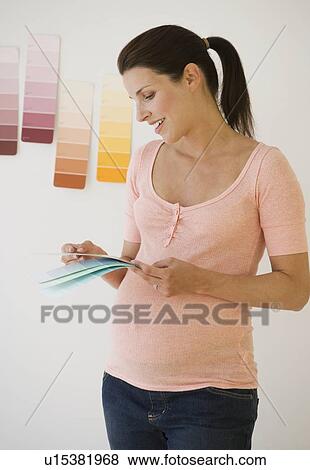 Stock Photo - Pregnant woman looking at paint swatches. Fotosearch