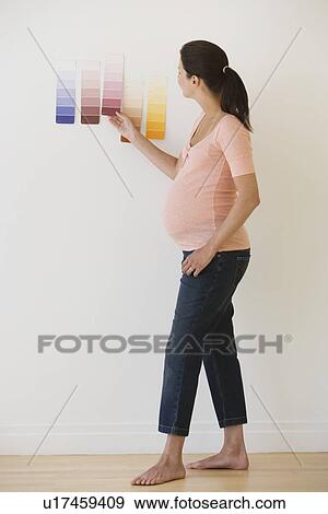 Stock Photo - Pregnant woman looking at paint swatches. Fotosearch