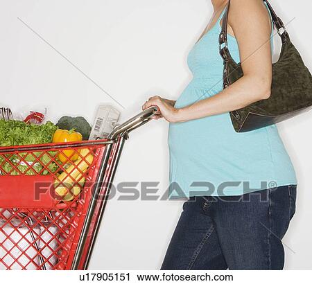 Stock Image - Pregnant woman pushing shopping cart. Fotosearch