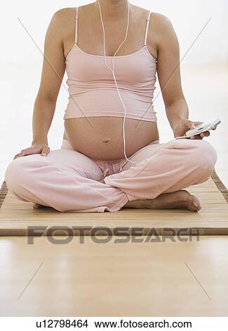 Pregnant woman sitting on yoga mat View Large Photo Image Picture - Pregnant woman sitting on yoga mat. Fotosearch