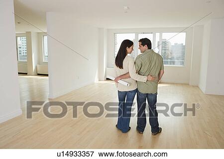 Rear view of couple with blueprints in empty house View Large Photo Image Stock Photo - Rear view of couple with blueprints in empty house. Fotosearch