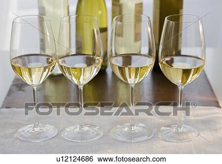 Row of wine glasses in front of wine bottles View Large Photo Image Stock Photograph - Row of wine glasses in front of wine bottles. Fotosearch
